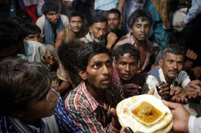Indian homeless men wait to receive free food